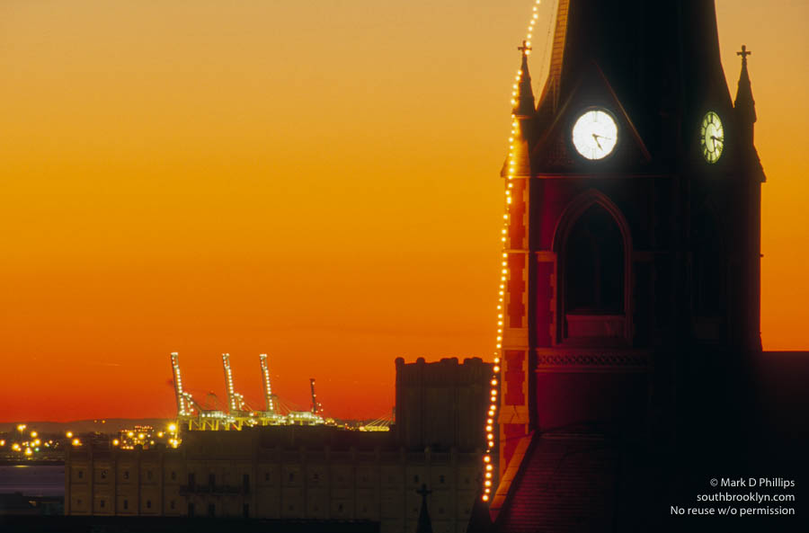 The Church of the Sacred Hearts of Mary and Jesus and St. Stephen clock tower in Carroll Gardens Brooklyn with Brooklyn Army Terminal and shipping cranes at sunset. ©Mark D Phillips