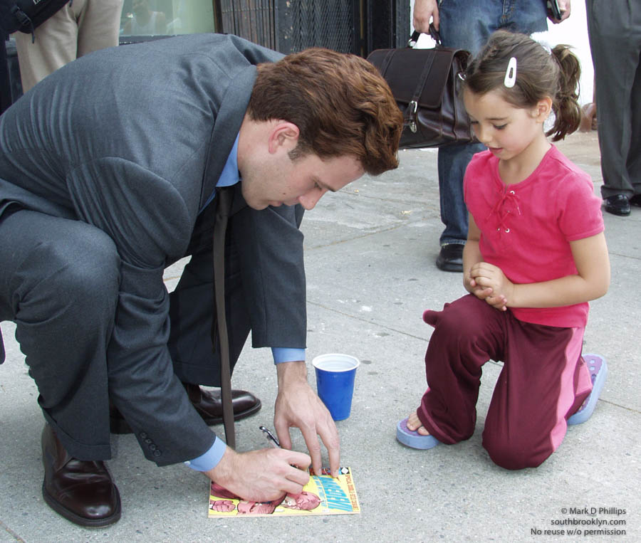 MOVIE MADNESS: Actor Ben Afleck stops on the street in Cobble Hill, Brooklyn, to sign an autograph on a comic book after a press conference with New York Senator Charles Schumer about the danger of shipping containers on the Brooklyn waterfront. ©Mark D Phillips