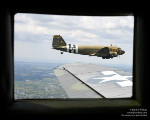 Betsy’s Biscuit Bomber flies off the wing of Placid Lassie, two of the D-Day Squadron of C47s. ©Mark D Phillips