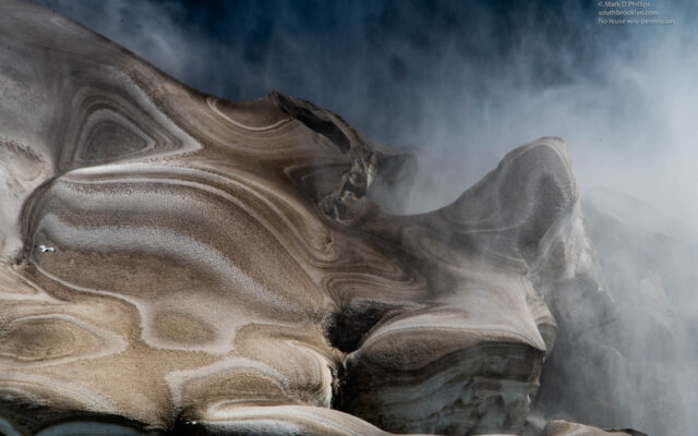 Ice at the base of the American falls of Niagara Falls looks like the skin of a dinosaur bathed in the mist from the water. The brown color and patterns feel prehistoric. ©Mark D Phillips
