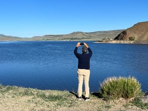 Colorado June 21, 2023; Mark D Phillips stands at the waterline of Blue Mesa Reservoir with the water at 90% capacity. ©Chuck Bigger